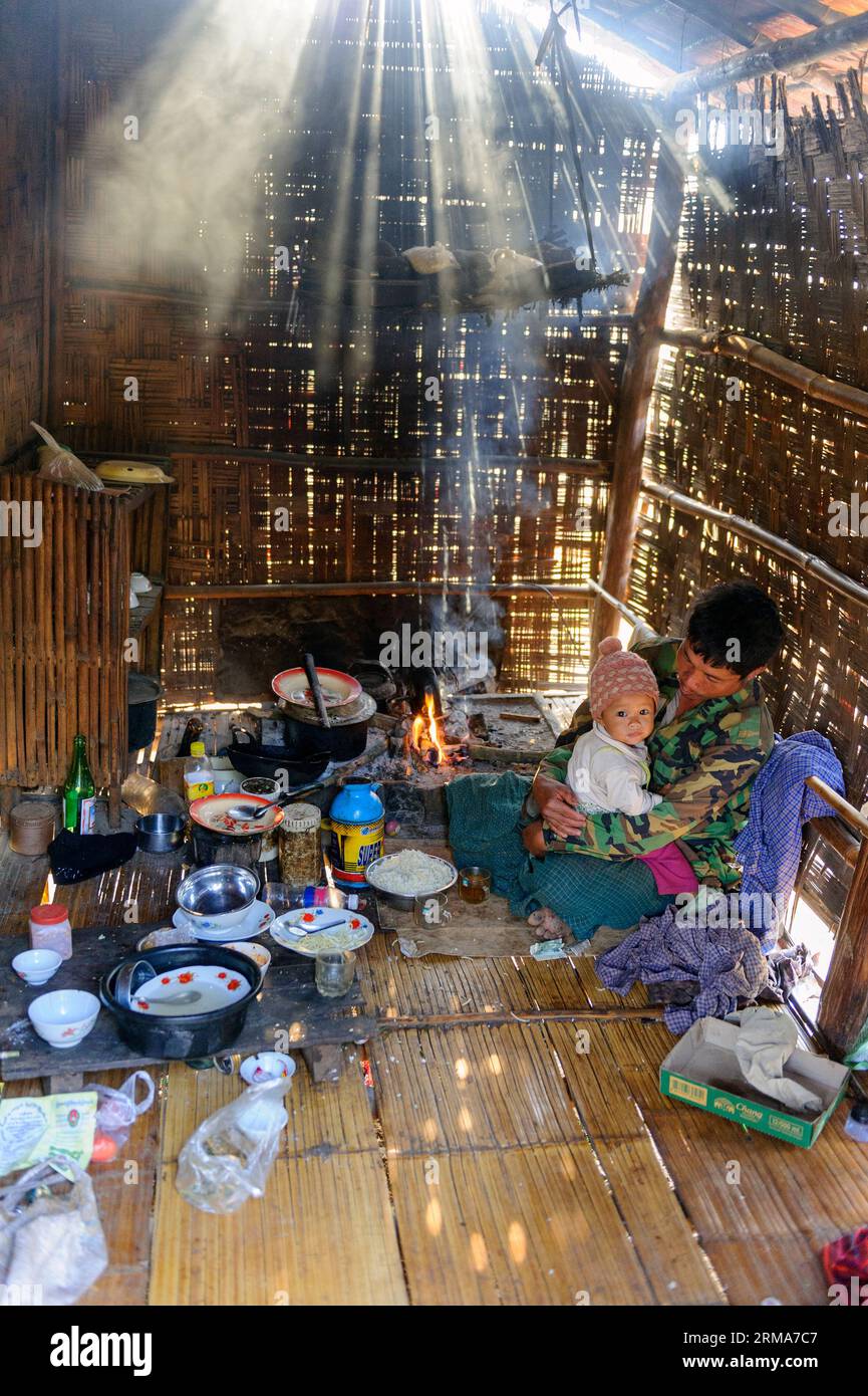 Farmer and child inside their woven bamboo house cooking dinner in the Taunggyi area of Shan, Myanmar, Burma Stock Photo