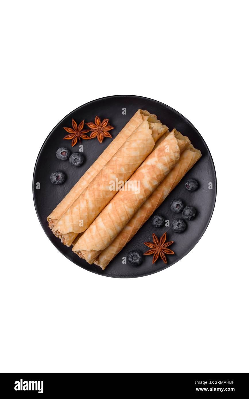 Delicious crispy wafer rolls with cream filling with nuts on a dark concrete background Stock Photo