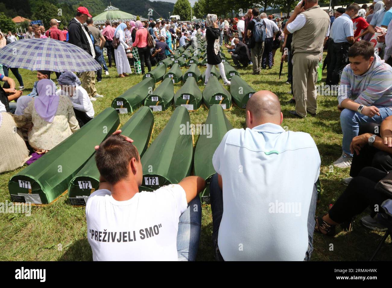 Relatives sitting next to coffins of the victims mourn before a funeral in Potocari, near Srebrenica, Bosnia and Herzegovina, July 11, 2014. The funeral of 175 recently identified victims was held here Friday to commemorate the 19th anniversary of the Srebrenica massacre. Some 7,000 Muslim men and boys were massacred in and near Srebrenica by Bosnian Serb forces in July 1995, the worst massacre in Europe since the end of World War II. (Xinhua/Haris Memija) (zjl) BIH-SREBRENICA-MASSACRE-19TH ANIVERSARY PUBLICATIONxNOTxINxCHN   Relatives Sitting Next to Coffin of The Victims Morne Before a Funer Stock Photo