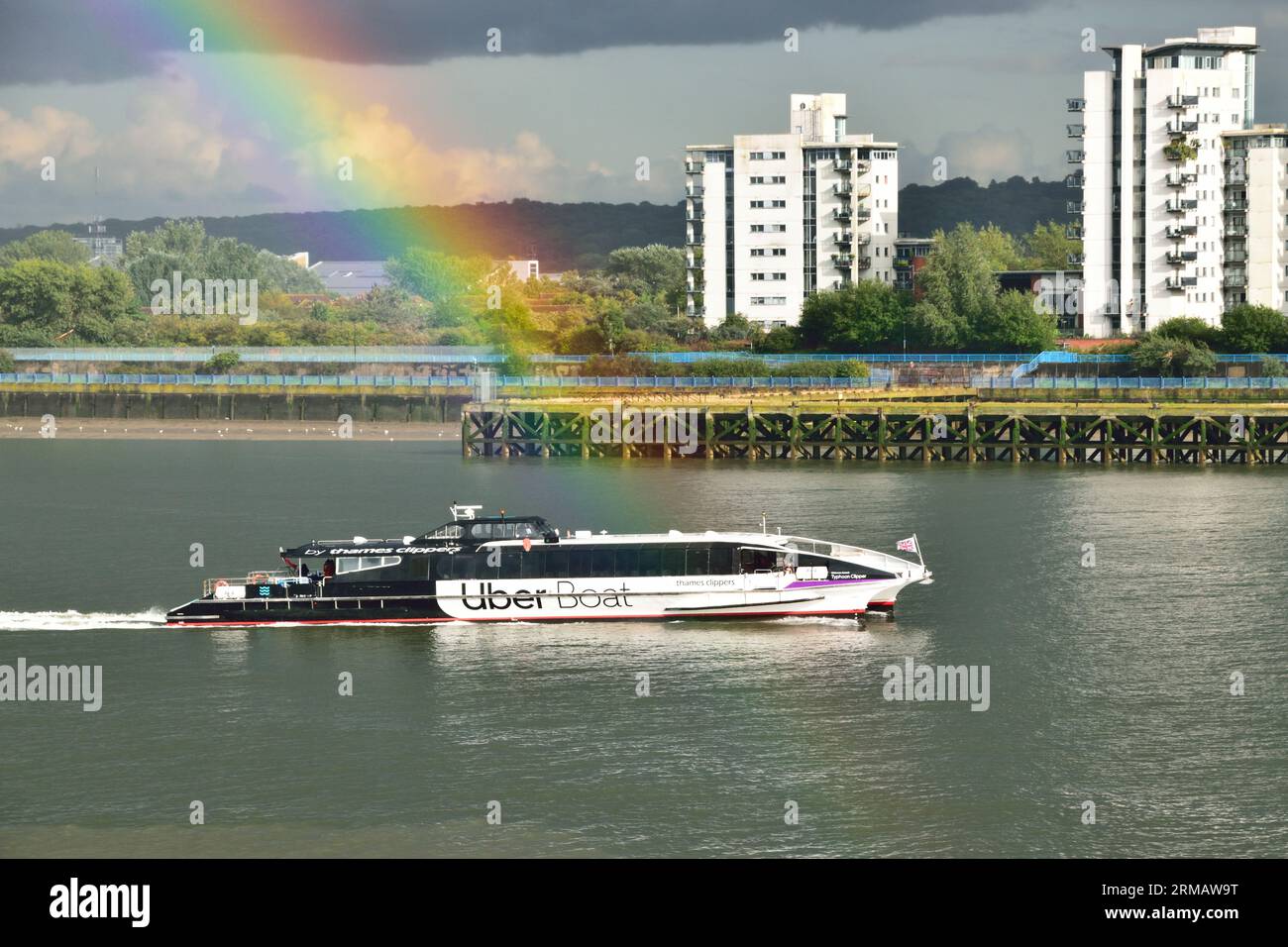 Uber Boat by Thames Clipper river bus service vessel Typhoon Clipper on the River Thames in London under stormy with a rainbow Stock Photo