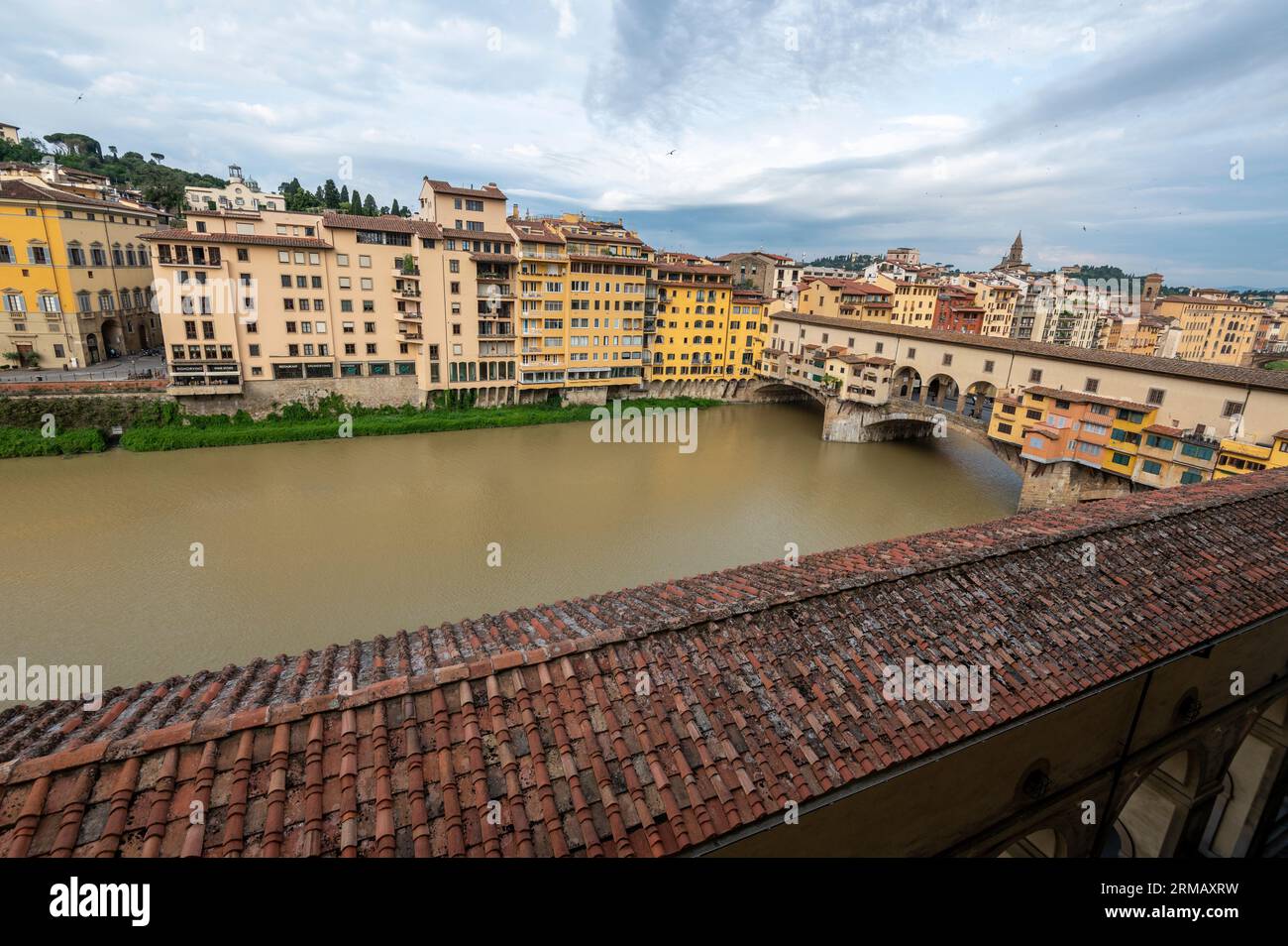 Over the top of the long tiled roof of the Lungarno degli Archibusieri is the south side of Florence on the river Arno, connected with the oldest Stock Photo