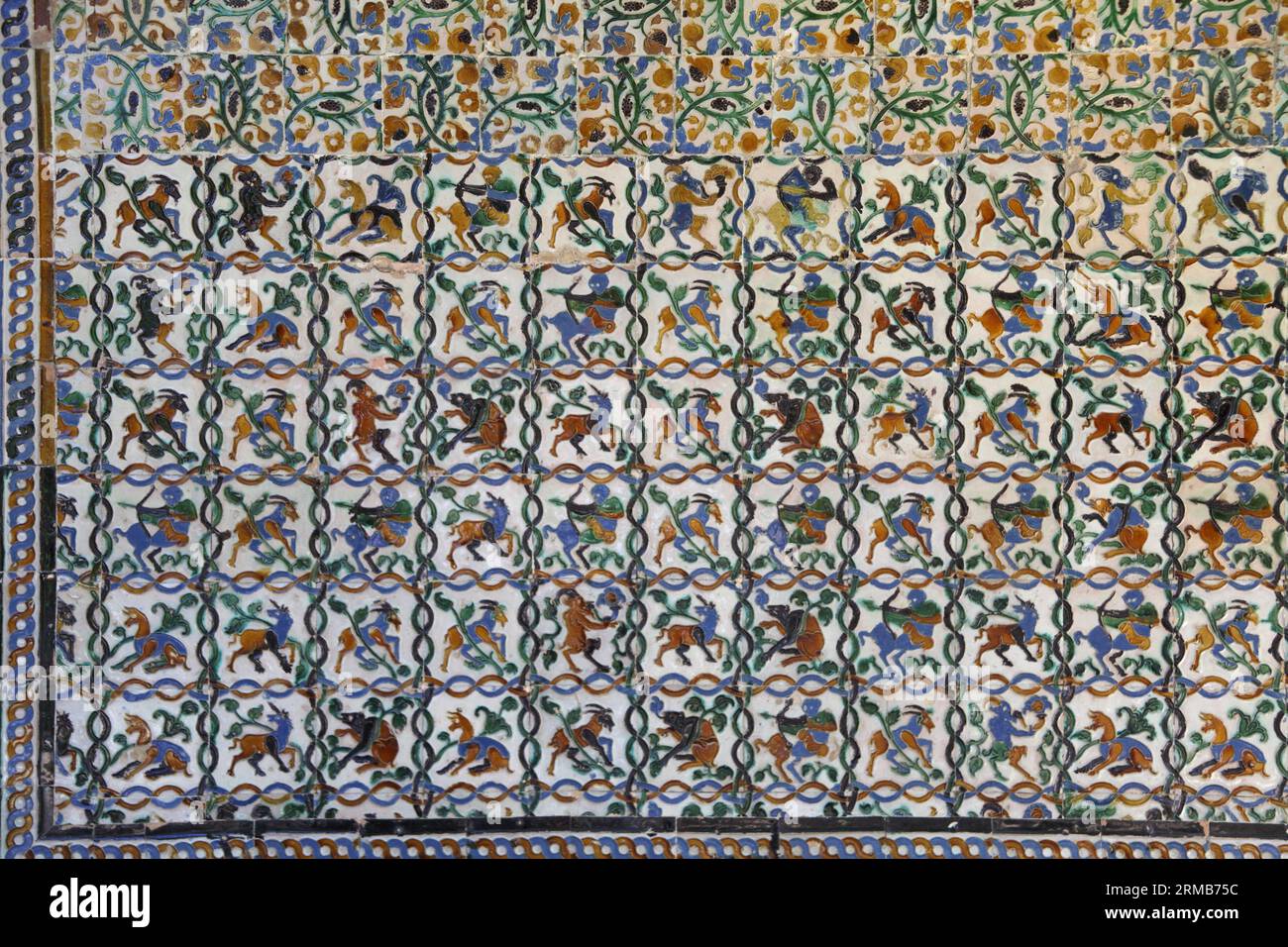 14th century Moorish tiled wall in Royal Alcazar palace gardens showing images of mythical creatures, Seville, Andalusia, Spain Stock Photo
