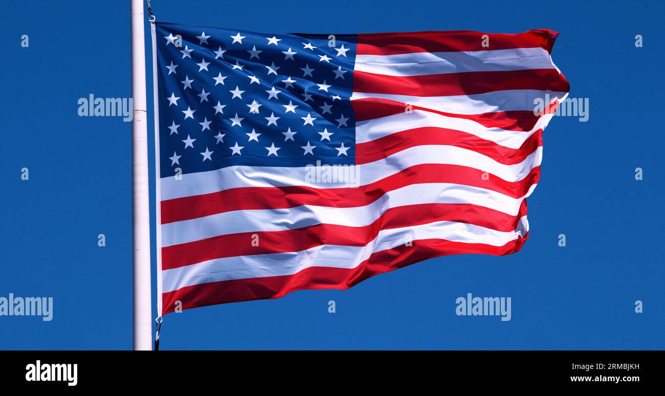 American Flag Waving in the Wind against blue sky Stock Photo - Alamy