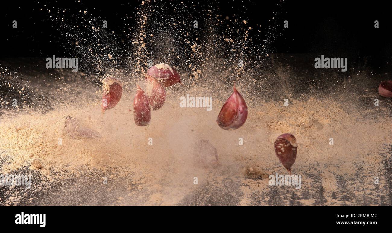 Garlic, allium savitum, Garlic pawns Falling on Garlic Powder on Black ...