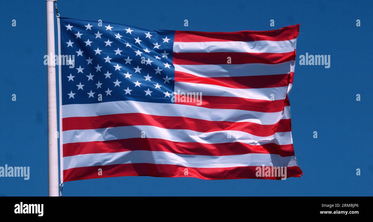 American Flag Waving in the Wind against blue sky Stock Photo - Alamy