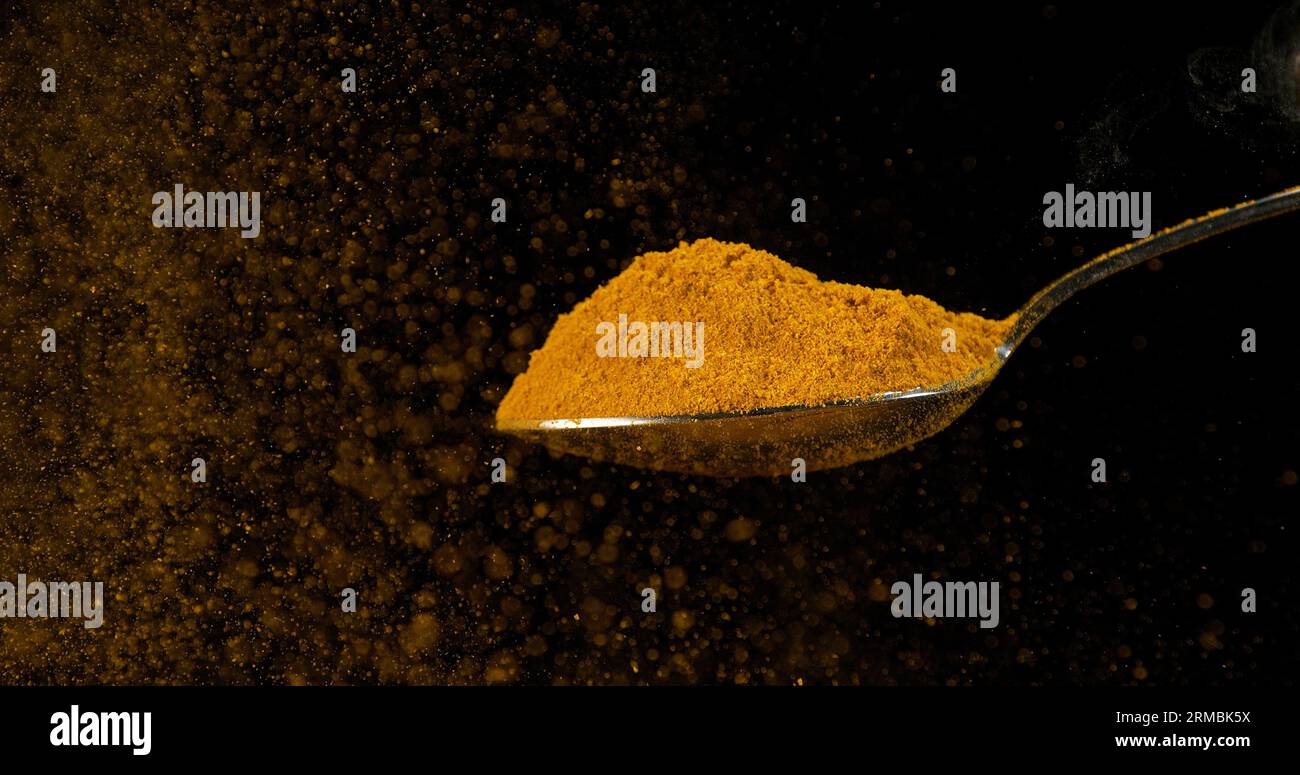 Spoon and Curry Powder falling from Spoon against Black Background ...