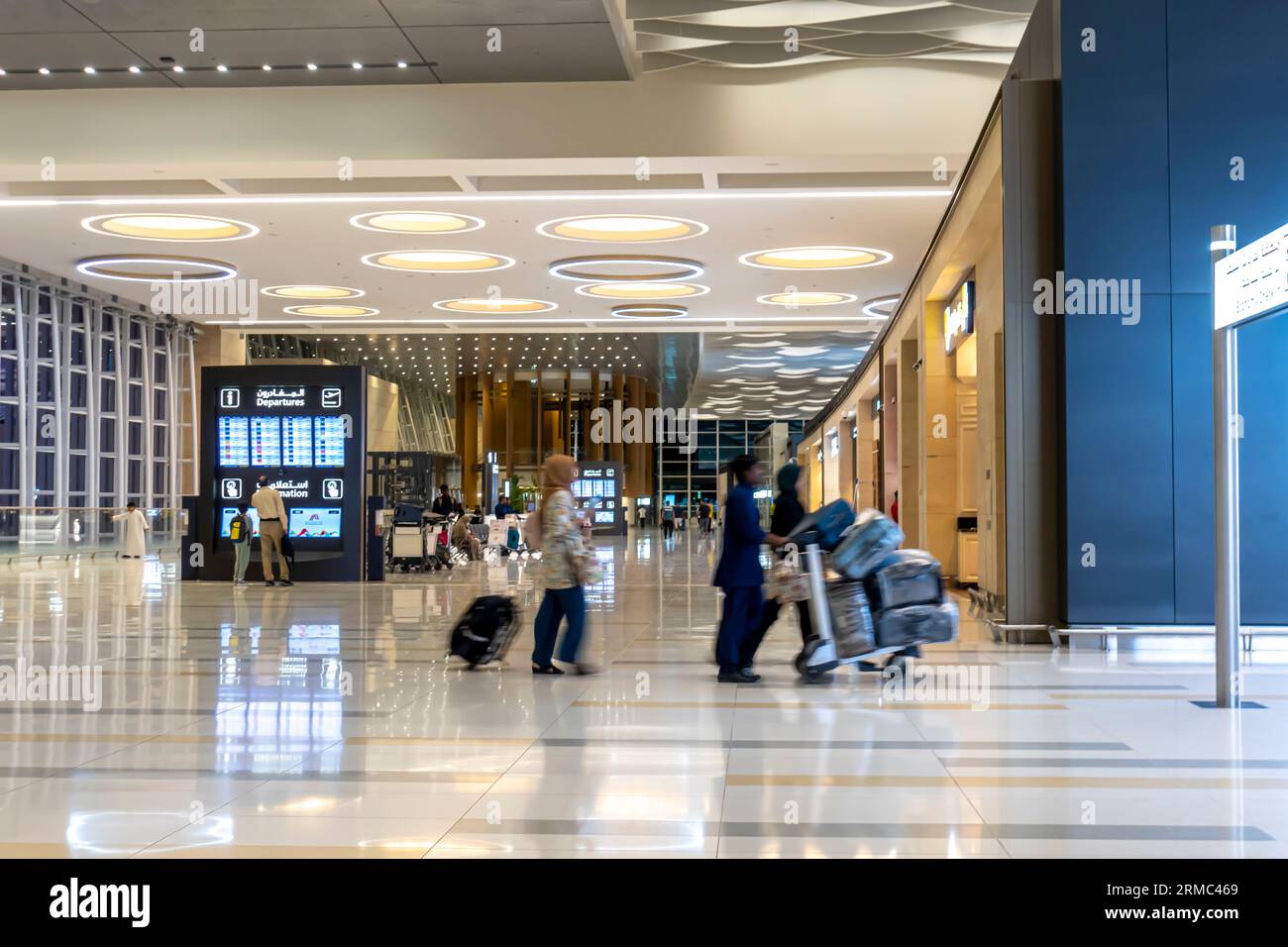 Bahrain airport interior. Passengers with carts luggage walking through