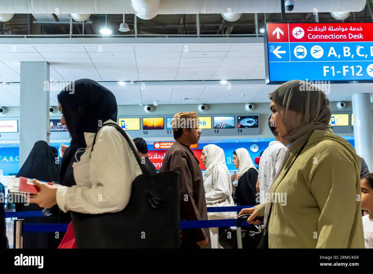 Female tourists arriving at Dubai airport - connected flights, signs. Dubai airport arrivals interior Stock Photo