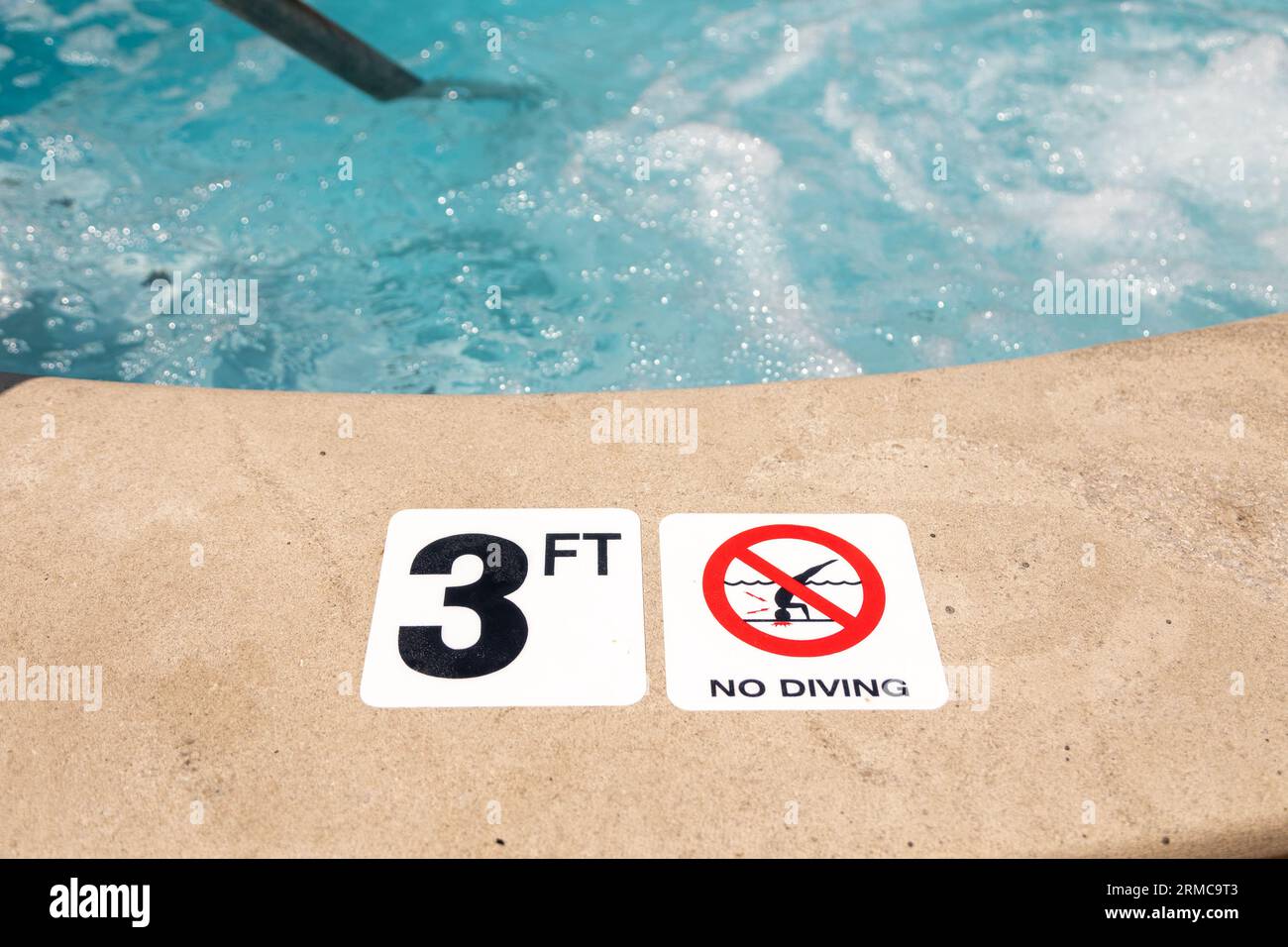 Edge of swimming pool with No Diving warning sign and 3 ft depth marker
