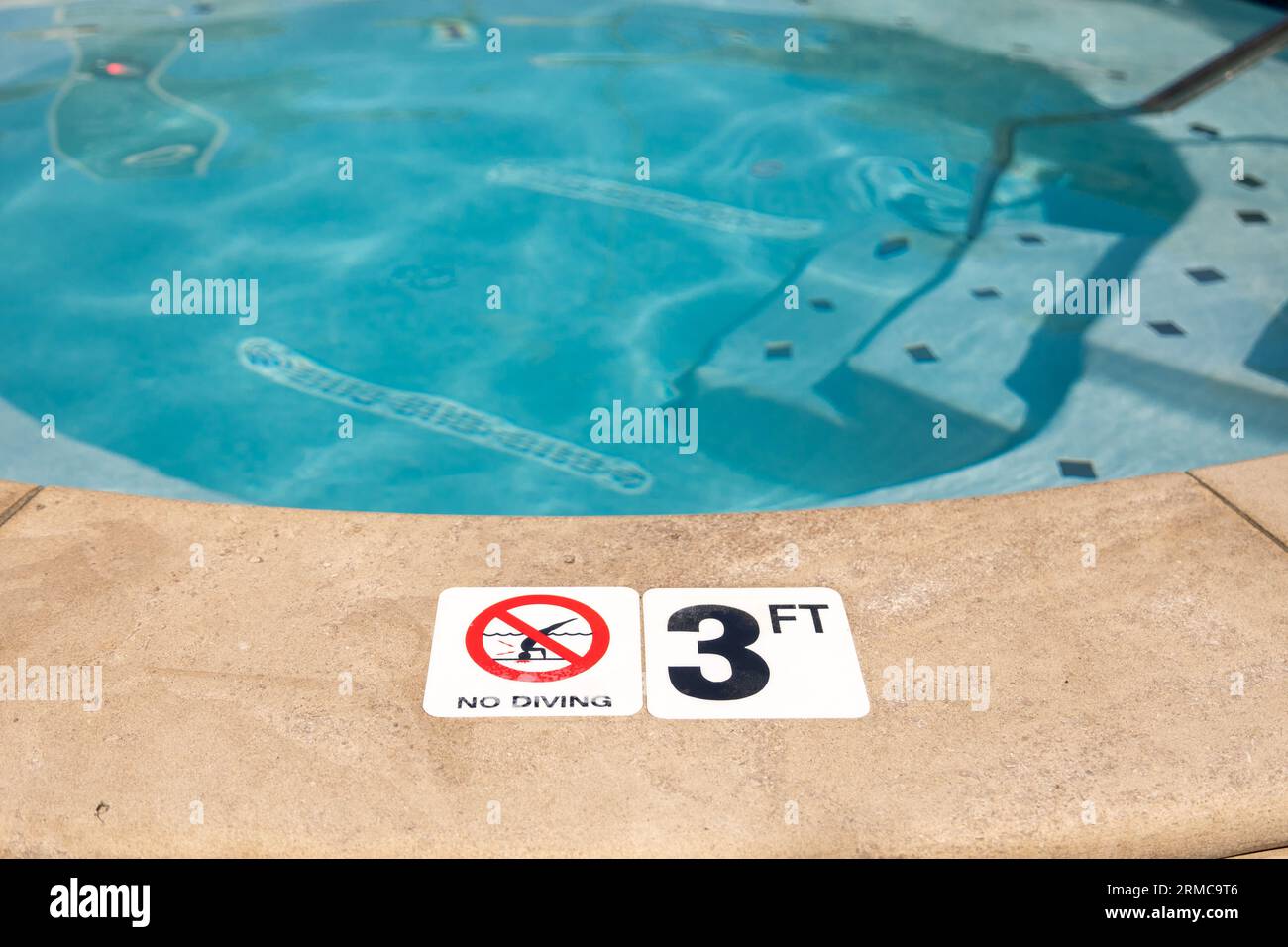 Edge of swimming pool with No Diving warning sign and 3 ft depth marker