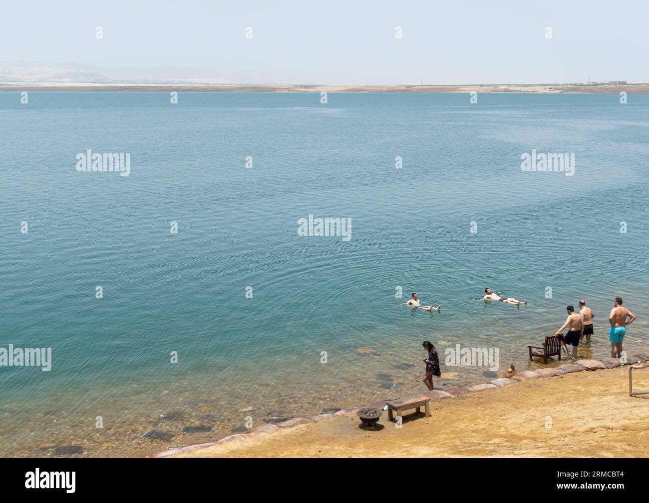 Tourists covered in mud swim in Dead Sea, Jordan Stock Photo