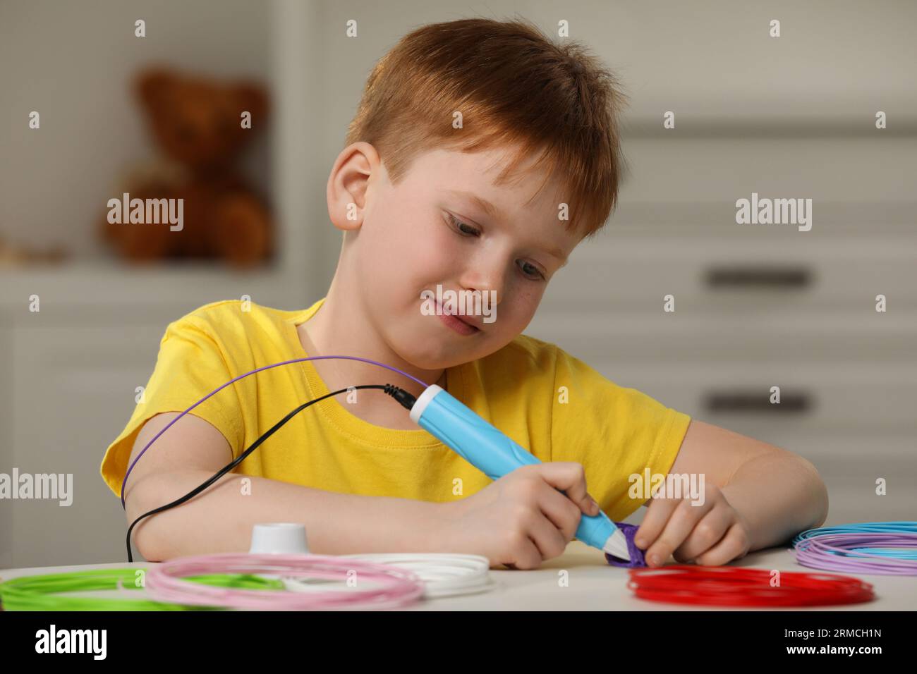 Boy drawing with stylish 3D pen at white table Stock Photo