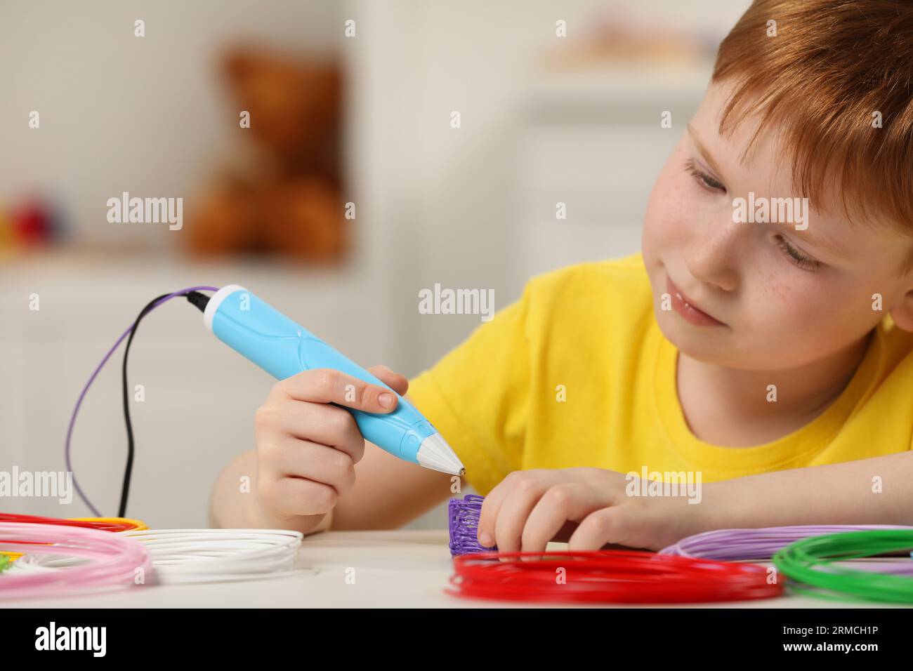 Boy drawing with stylish 3D pen at white table Stock Photo