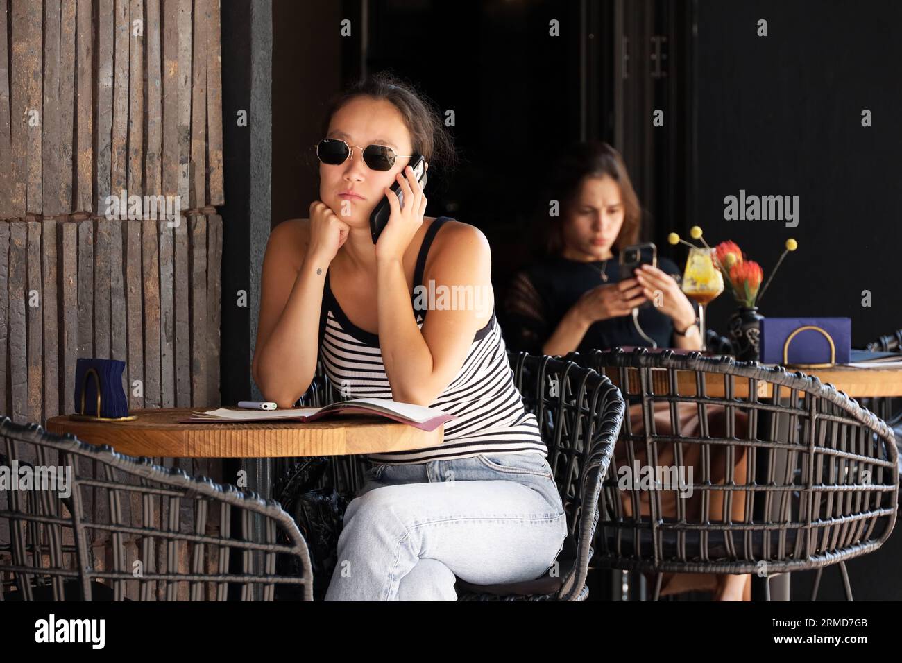 Women sitting with smartphones in street cafe. Life in summer city, online communication Stock Photo