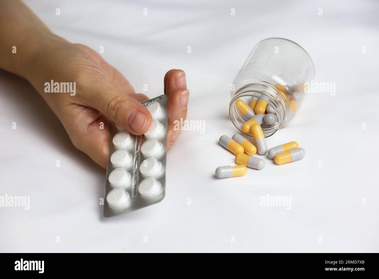 Pills in a palm of female hand on the bed. Concept of medication, vitamins or sleeping pill Stock Photo