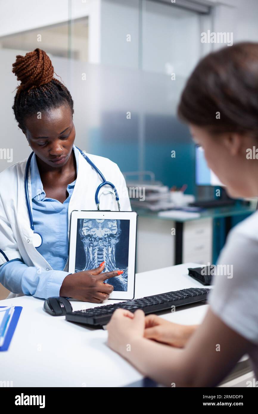 Radiology specialist doctor with x-ray ct scan of cervical injury giving medical result to patient during clinical appointment. Radiologist presenting treatment for soreness, pain, ache symptoms Stock Photo