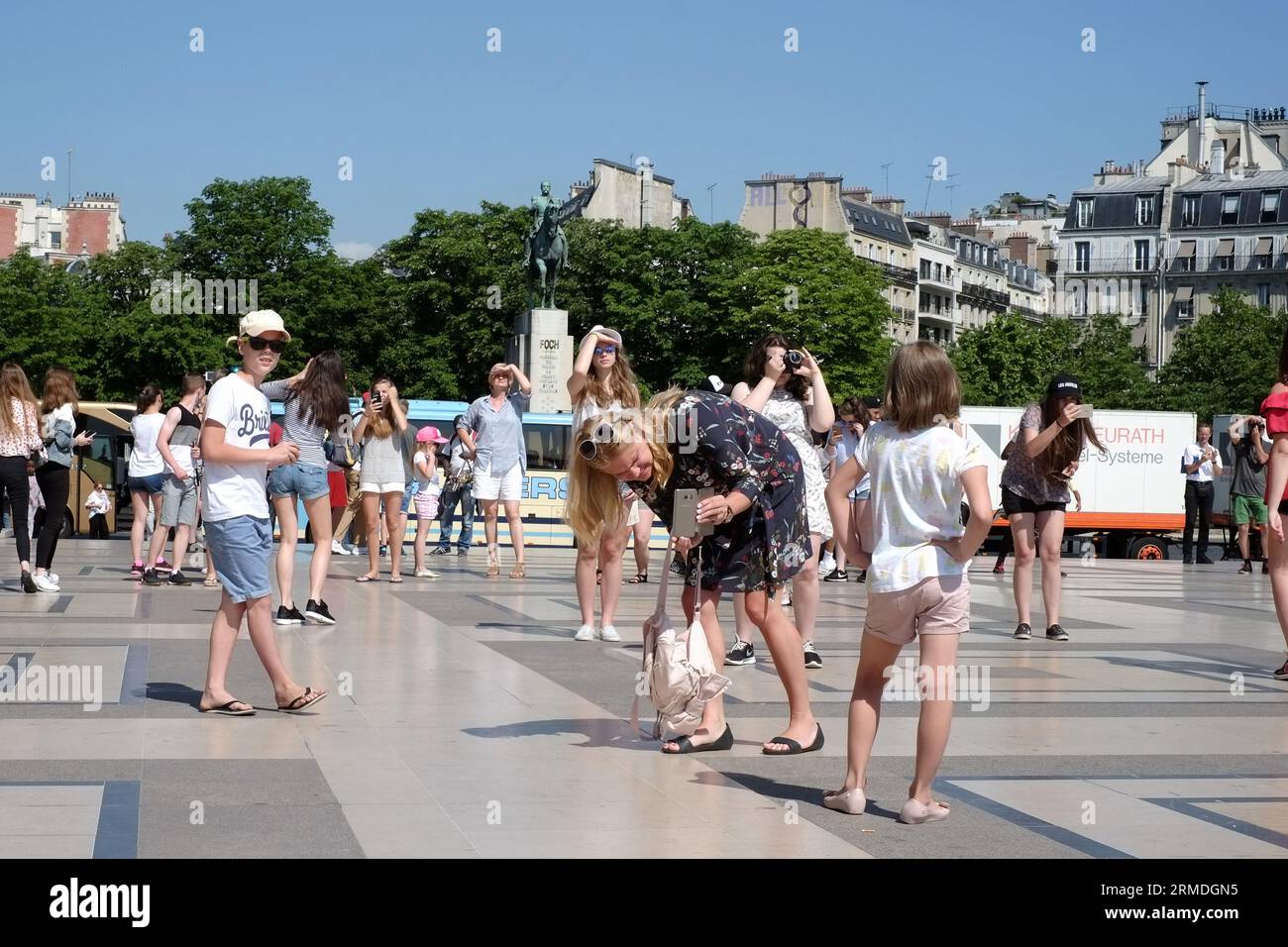 In Place du Trocadéro a mother bends double photographing her young daughter with 'Paris's best view of the Eiffel Tower' on a sunny summer day Stock Photo