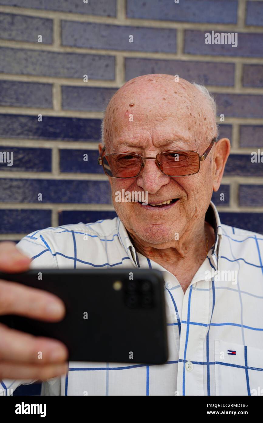 Old man taking selfie by cellphone. Technology and elderly active lifestyle Stock Photo