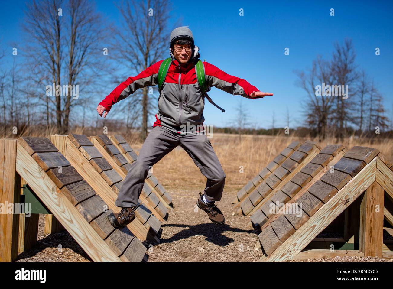 A man with a backpack leaps across ramps in obstacle course outside ...