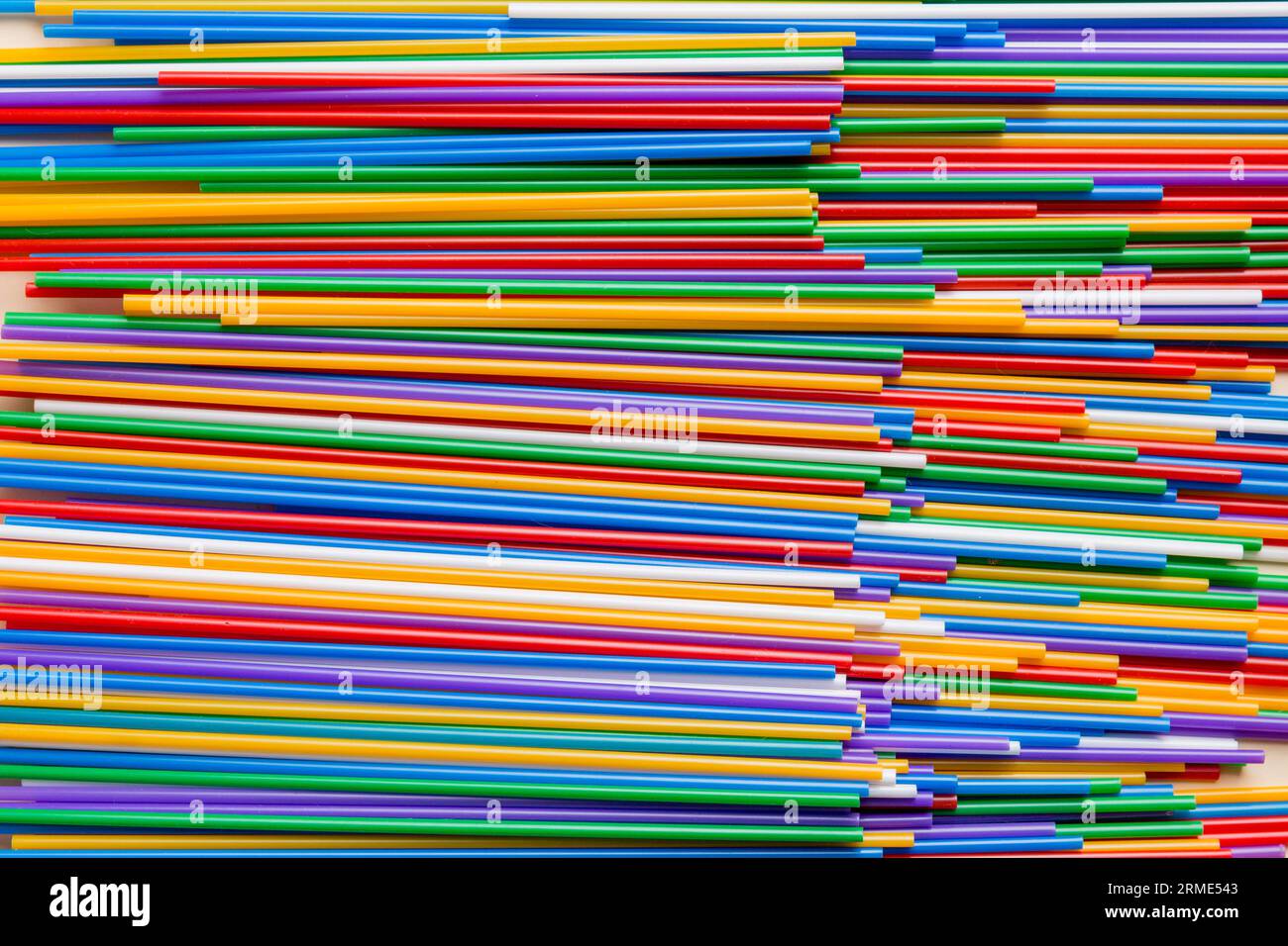 many multi-colored plastic tubes for cocktail on Colored background, top view. Stock Photo