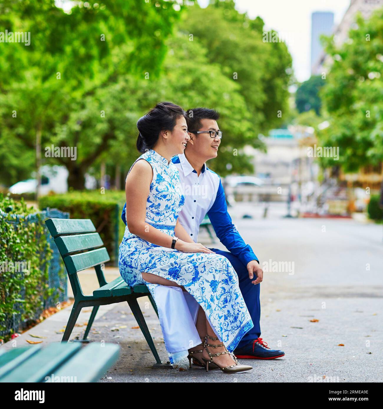 Young romantic Asian couple sitting on bench near the Eiffel Tower ...