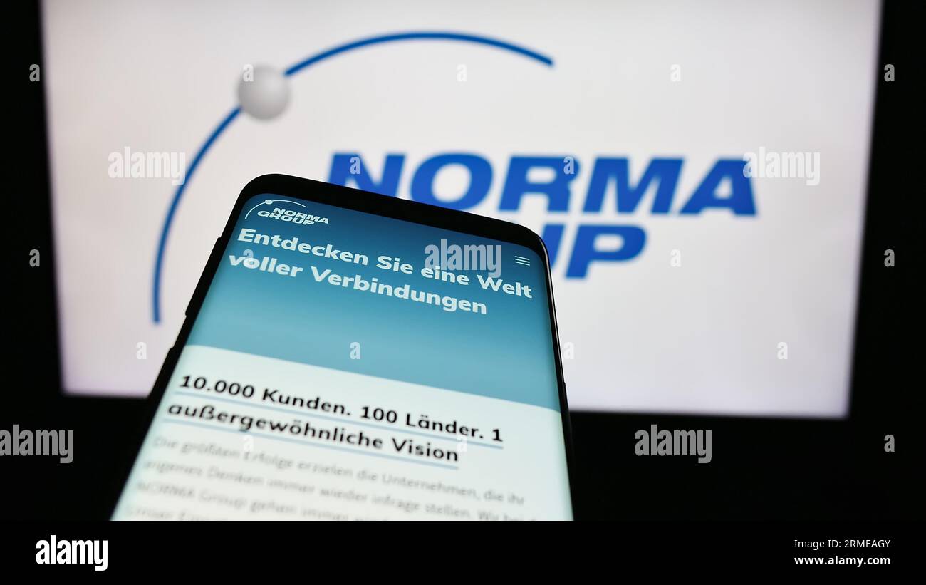 Smartphone with webpage of German manufacturing company Norma Group SE on screen in front of business logo. Focus on top-left of phone display. Stock Photo