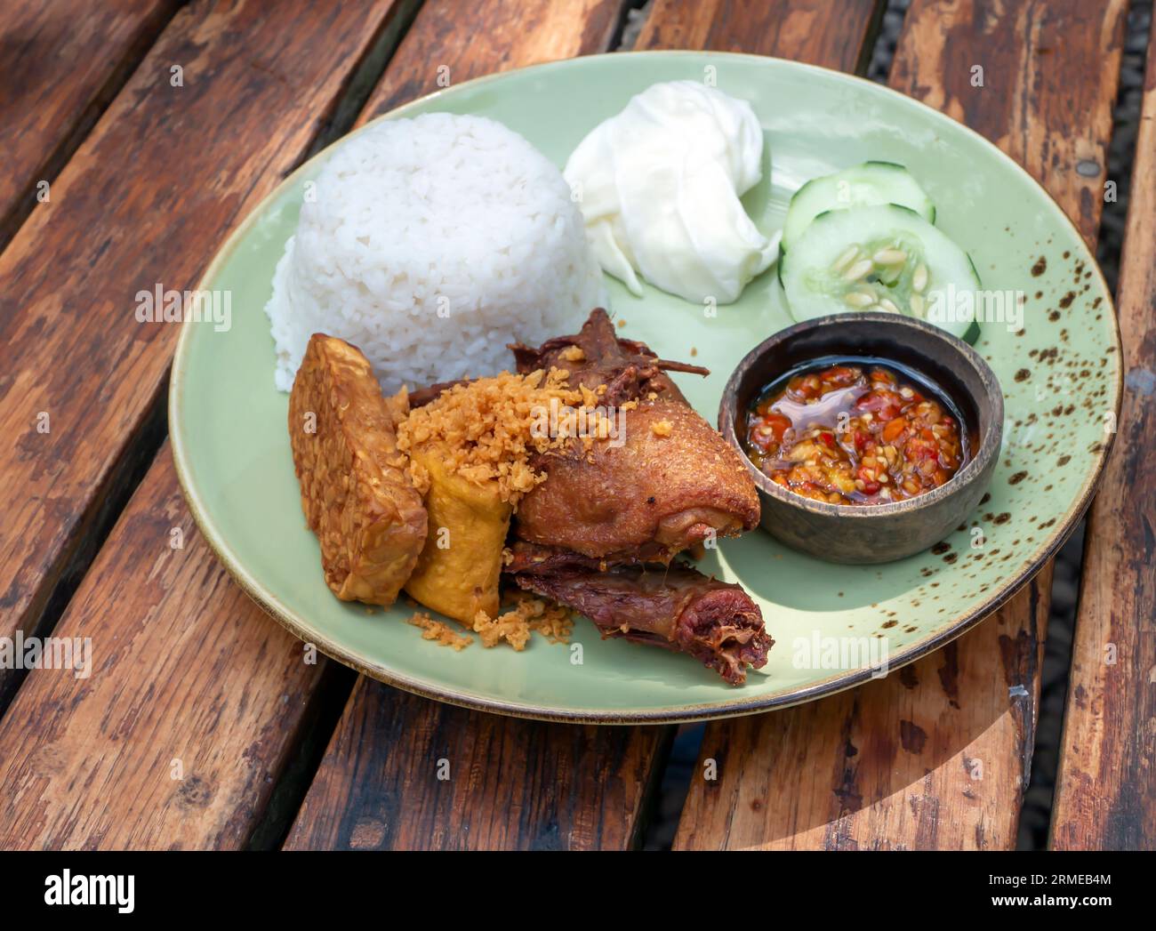Bebek Goreng Kremes,  deep fried duck, Indonesian traditional food, served with chili sauce (sambal) and cucumber. Stock Photo