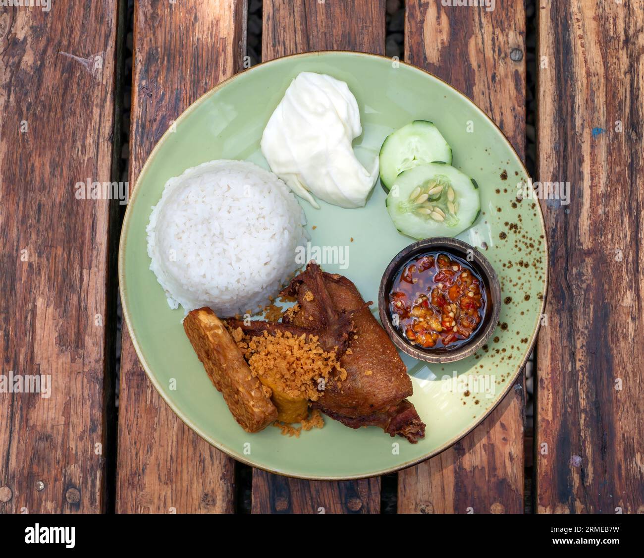 Bebek Goreng Kremes,  deep fried duck, Indonesian traditional food, served with chili sauce (sambal) and cucumber. Stock Photo