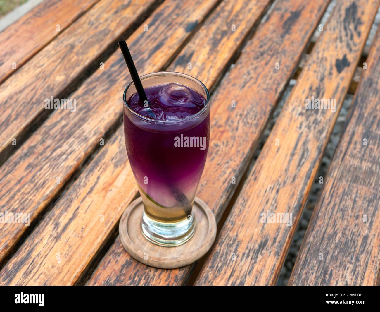 Close up a glass of fresh butterfly pea drink, Clitoria ternatea, on old wooden table. Stock Photo