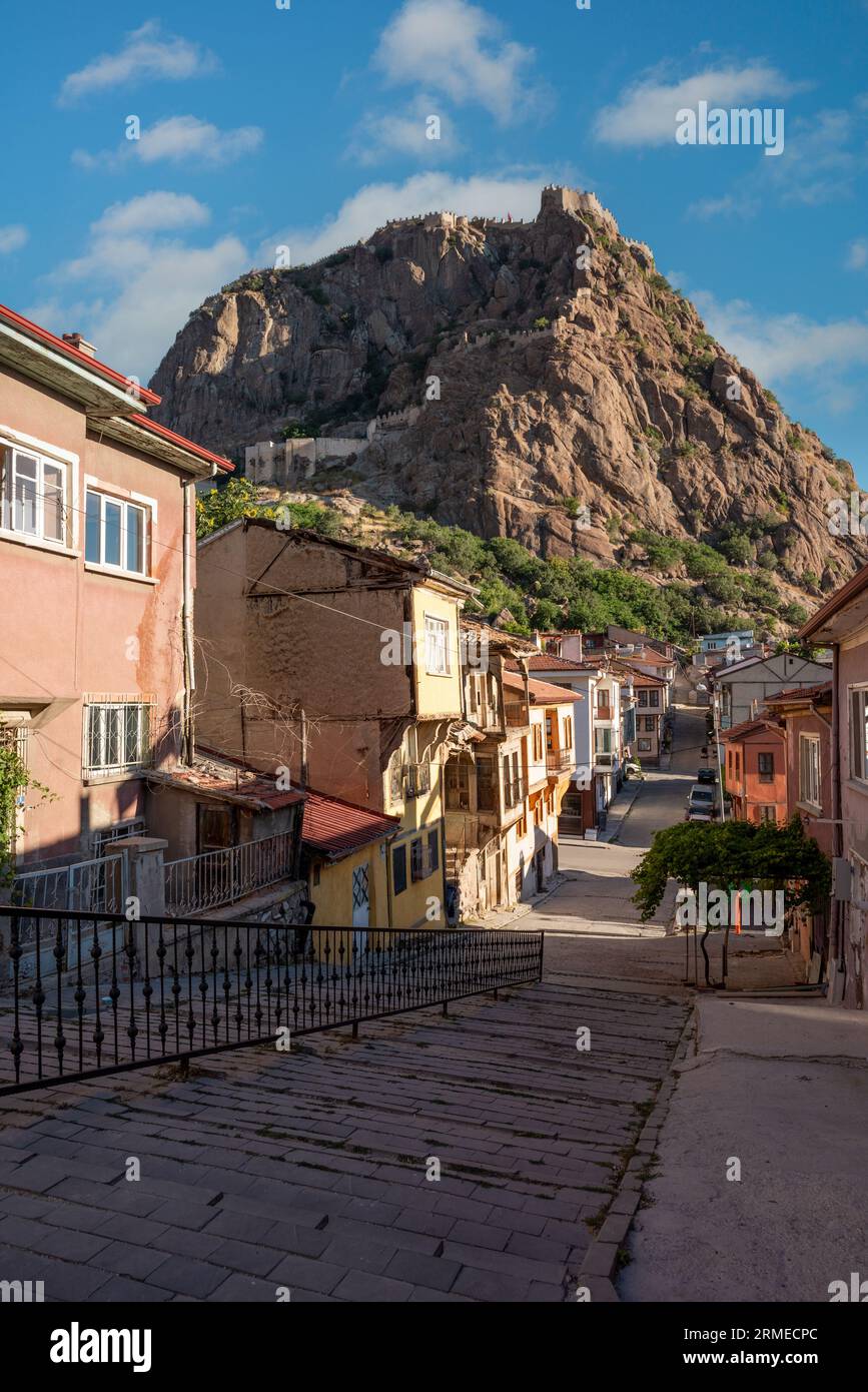Traditional Turkish Ottoman houses in Afyonkarahisar Turkey. Afyon Castle on the rock and Mevlevihane Museum in front of it Stock Photo