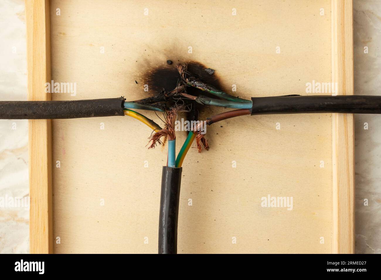 Charred plywood texture under burned faulty wiring, short circuit fire hazard concept, close up Stock Photo