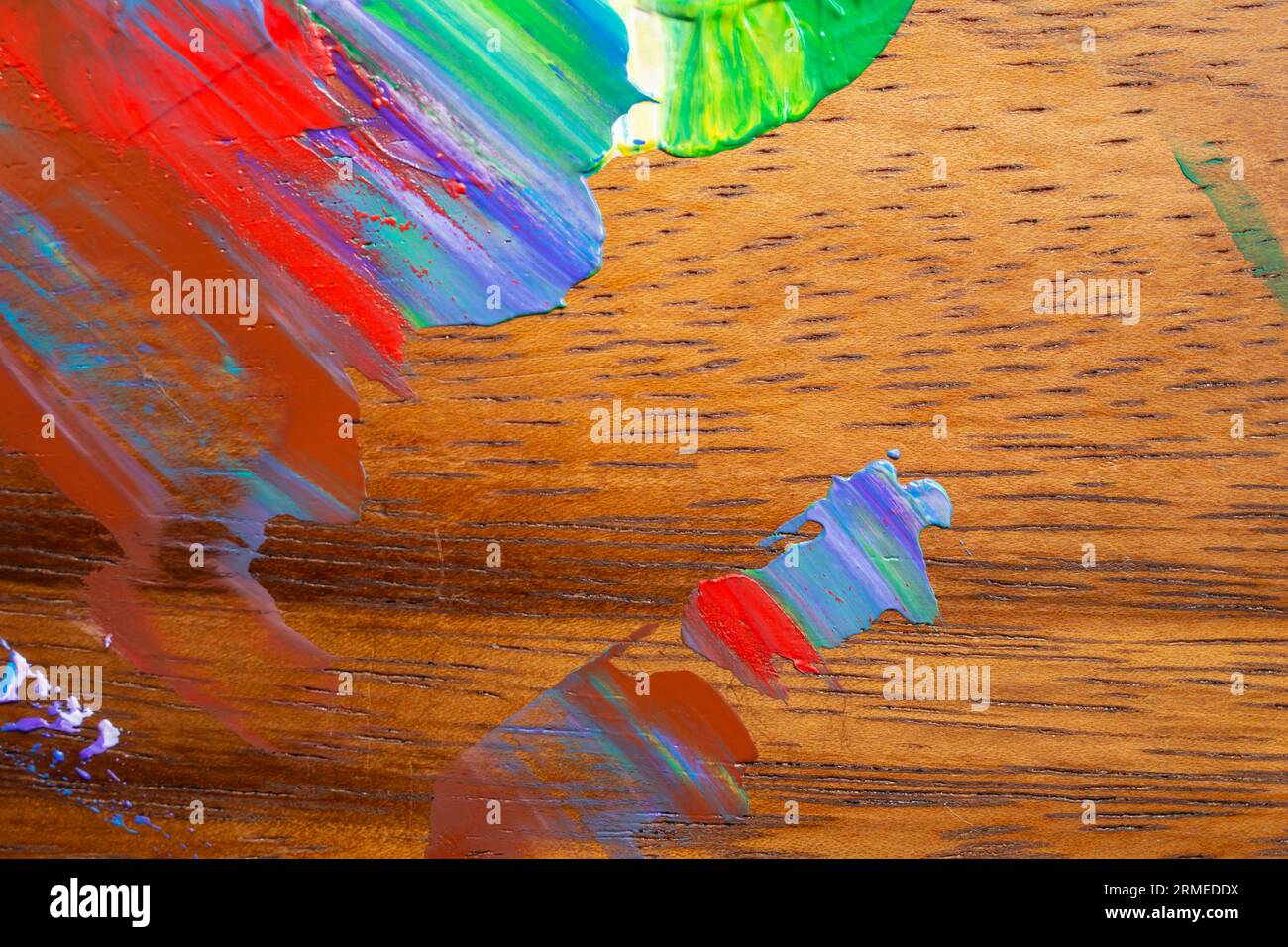 Multiple colors acrylic paint smudged on hardwood furniture, close up