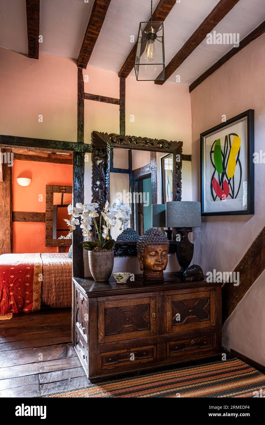 Orchid and Buddha's head on vintage chest in timber framed Tudor farmhouse, Surrey, UK Stock Photo
