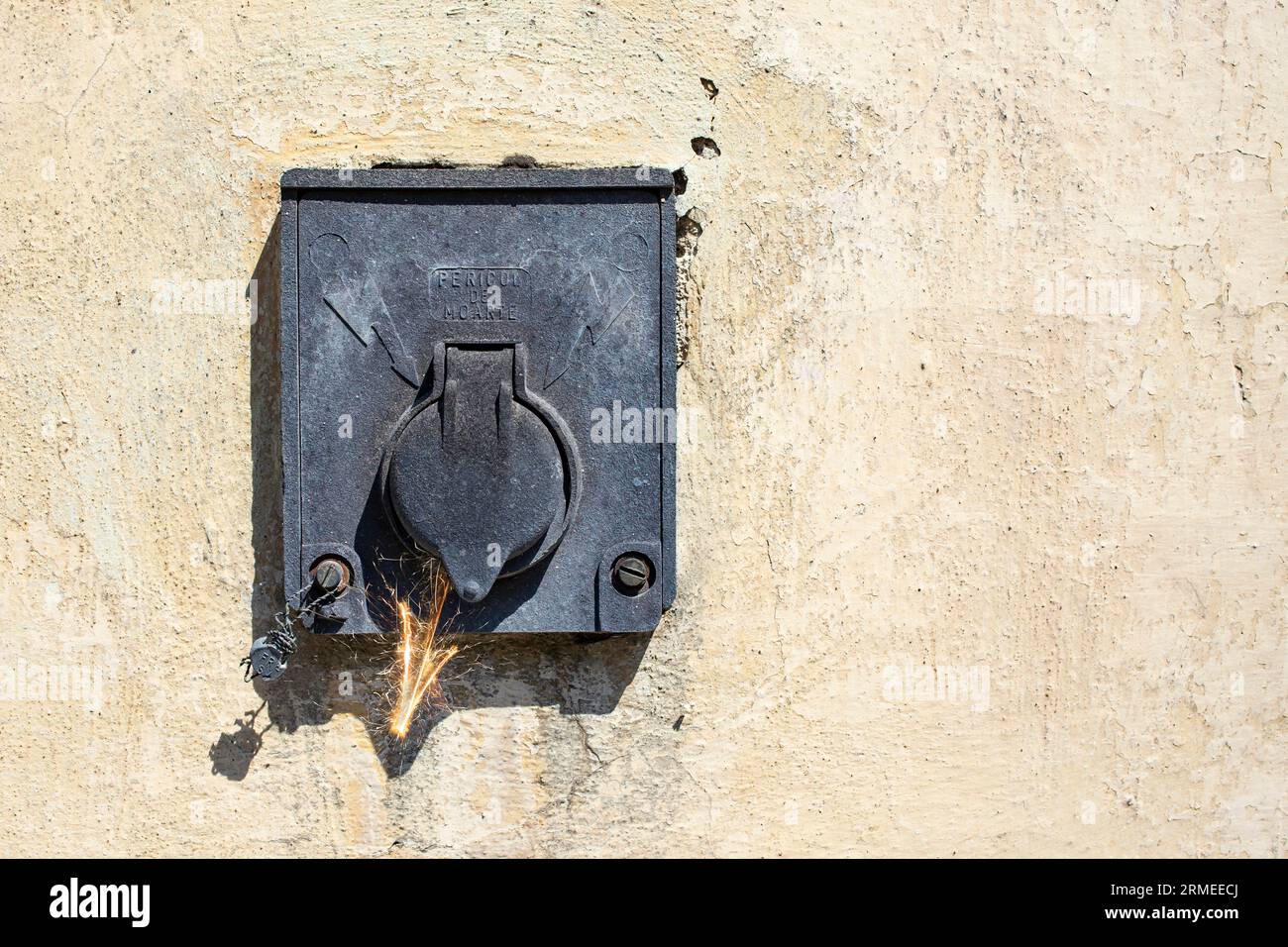 Old black electrical appliance on vintage wall texture, with sparks arrow, short circuit concept Stock Photo