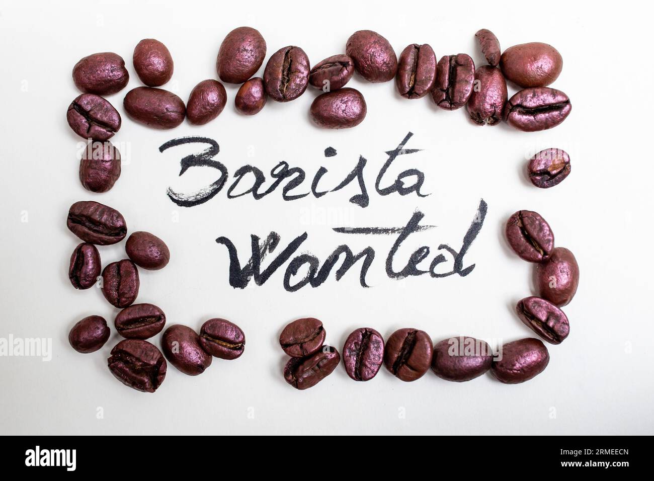 Barista wanted written with black paint on white paper in a pink coffee beans frame, recruitment