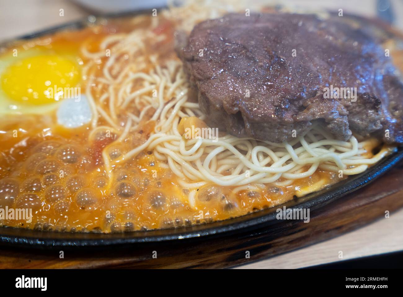 Taiwanese style special sizzling beef steak with noodles, egg and sauce on an hot iron board in traditional night market. Stock Photo