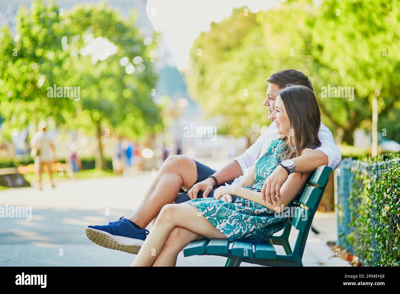 Happy dating couple hugging on a bench in a Parisian park near the Eiffel tower Stock Photo