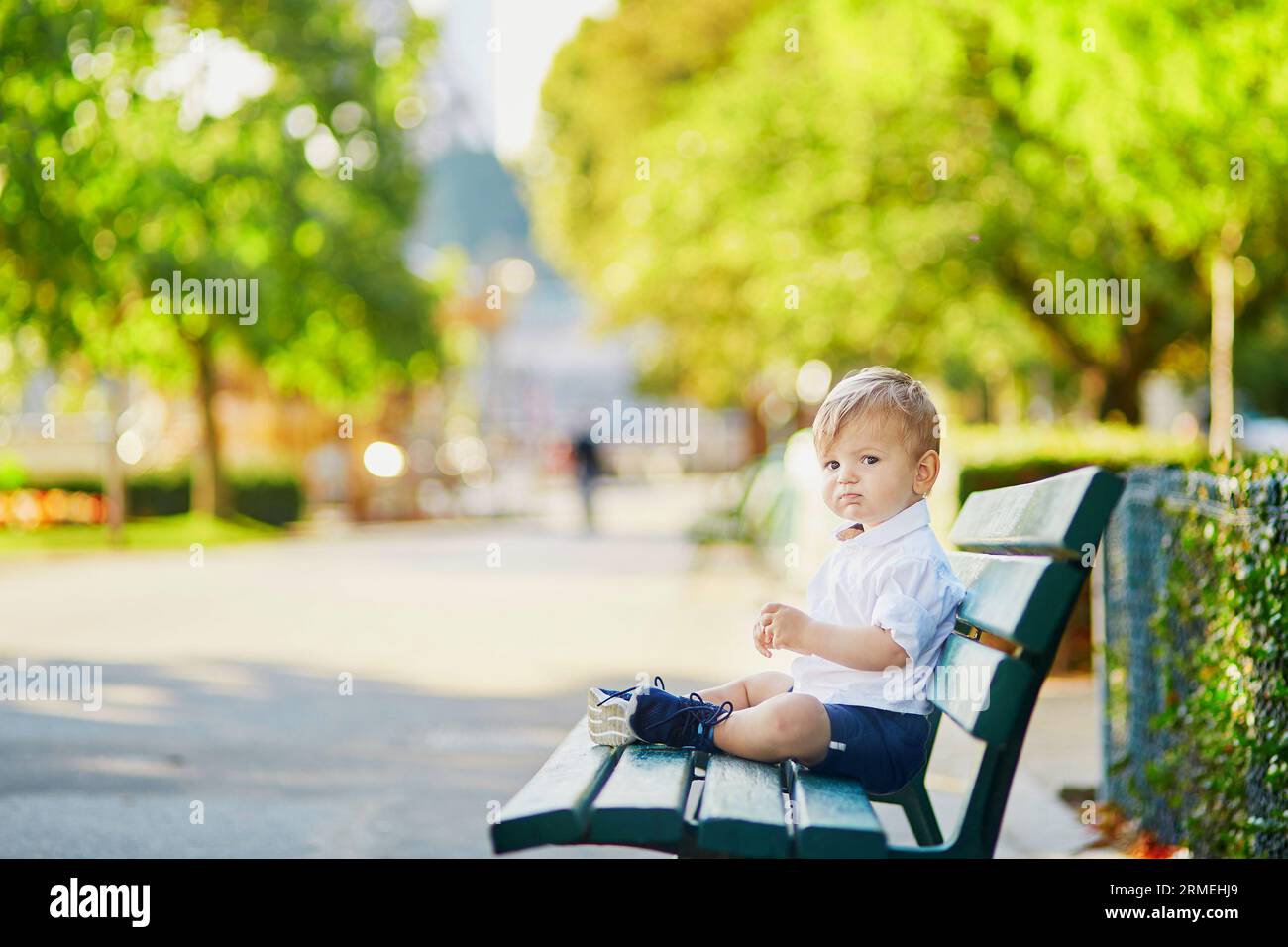Cute little boy sitting on the bench in park Stock Photo - Alamy