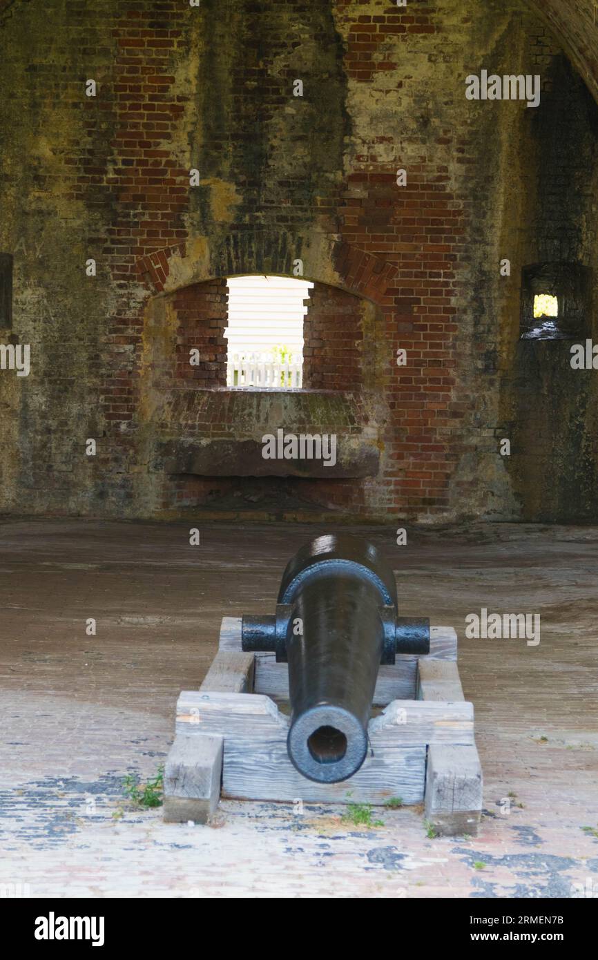 A historic cannon displayed in a room of an old fort, its metallic ...
