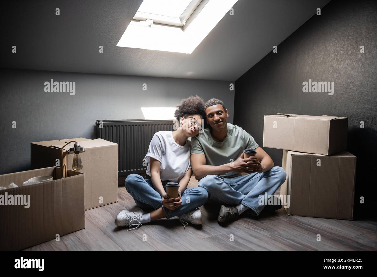 https://c8.alamy.com/comp/2RMER25/smiling-african-american-couple-holding-coffee-to-go-while-sitting-near-boxes-on-attic-in-new-house-2RMER25.jpg