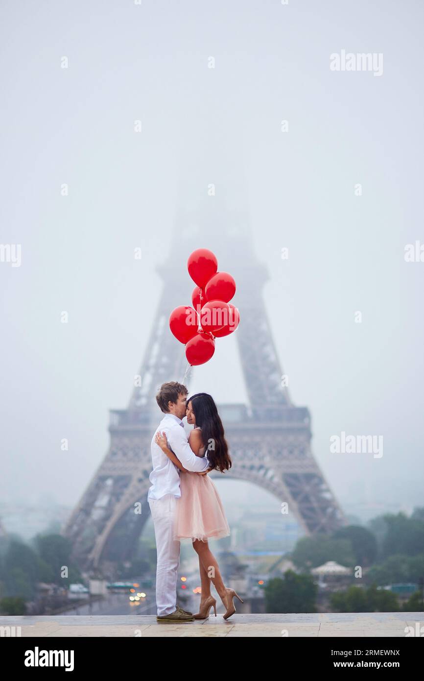 Beautiful romantic couple in love with bunch of red balloons together ...