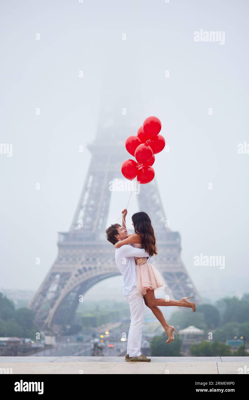Beautiful romantic couple in love with bunch of red balloons together ...