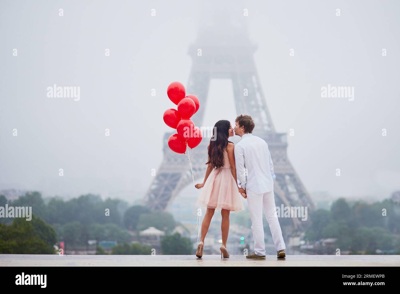 Beautiful romantic couple in love with bunch of red balloons together ...