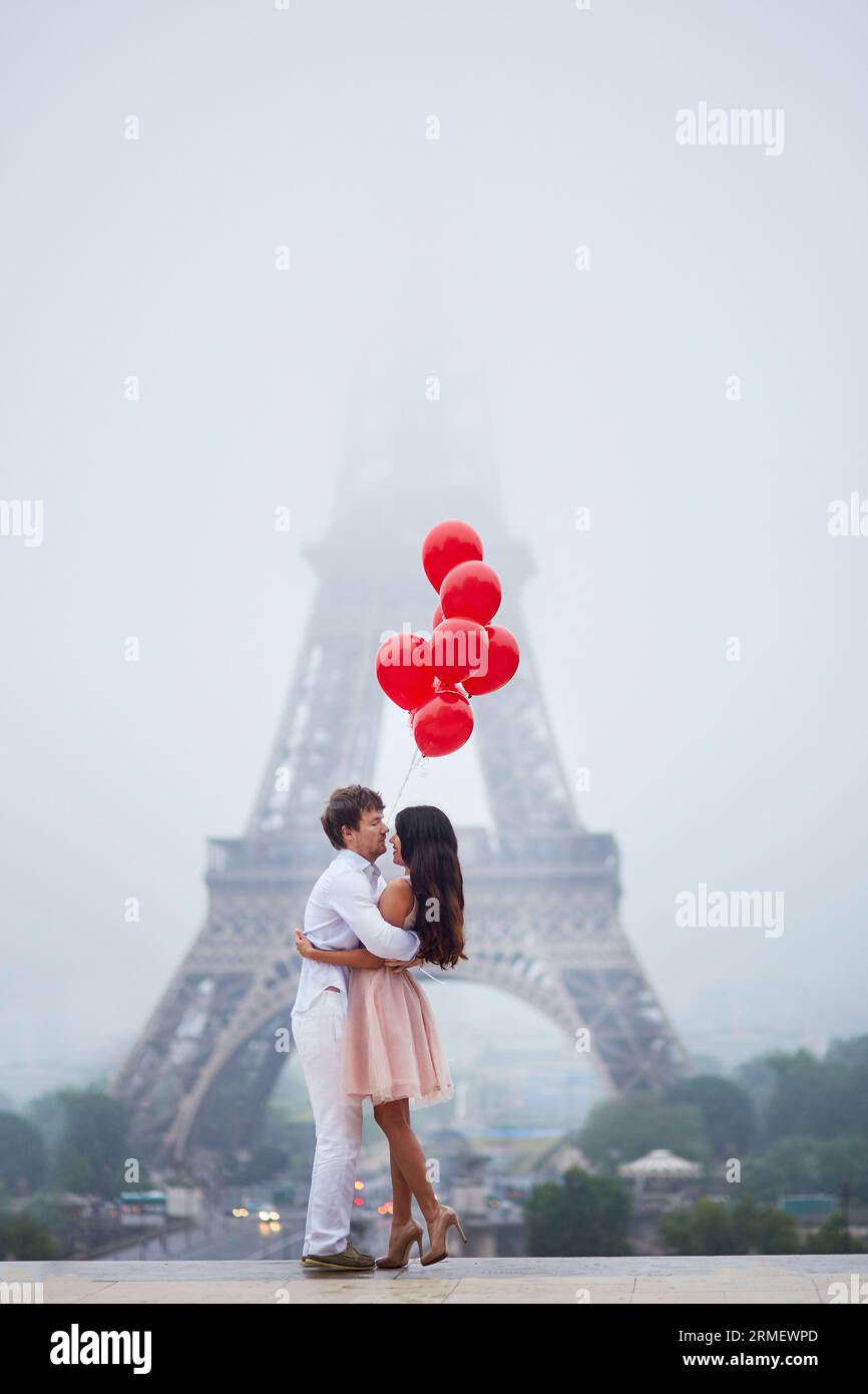 Beautiful romantic couple in love with bunch of red balloons together ...