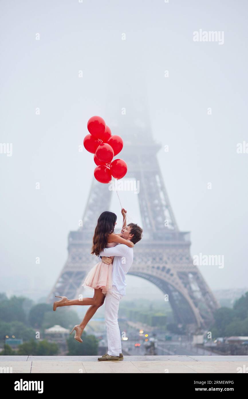 Beautiful romantic couple in love with bunch of red balloons together ...