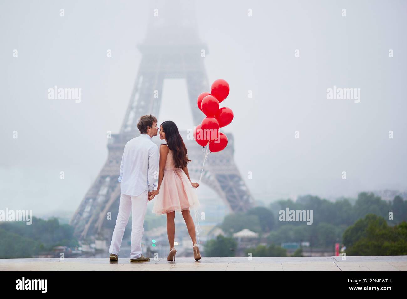Beautiful romantic couple in love with bunch of red balloons together ...