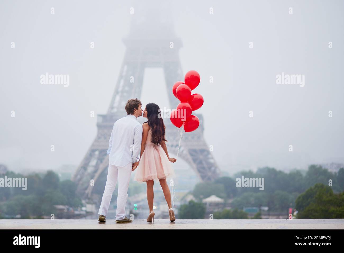 Beautiful romantic couple in love with bunch of red balloons together ...