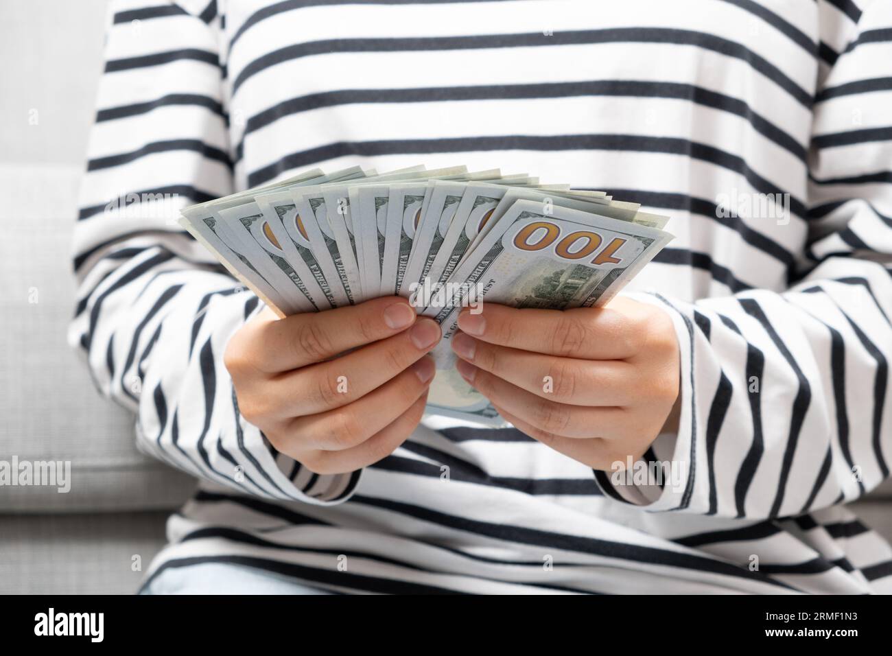 A woman counts hundred-dollar bills, hands close-up. Stock Photo