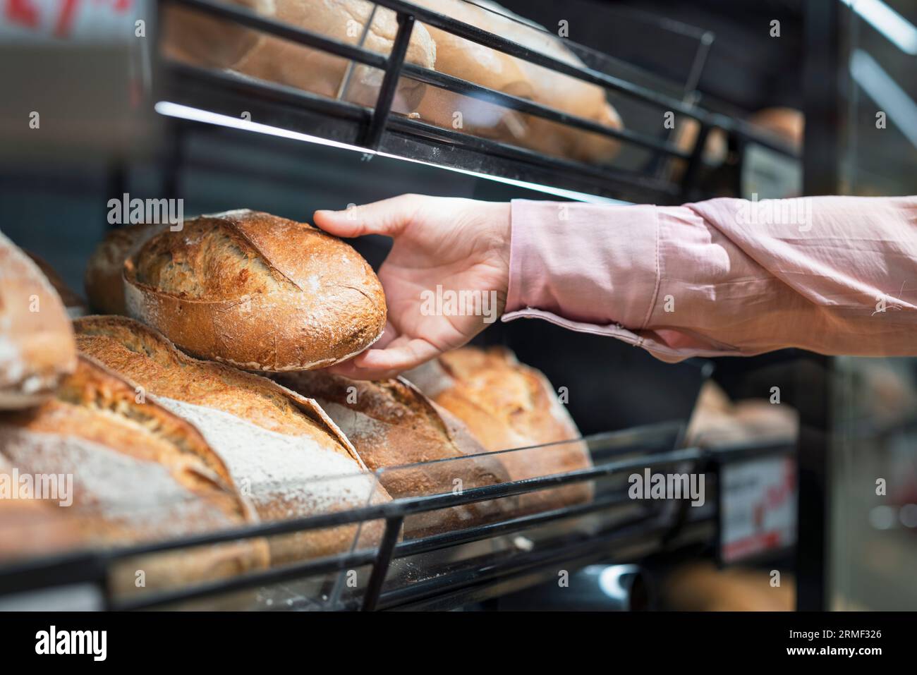 Close-up of man picking bread in bakery section of supermarket Stock Photo