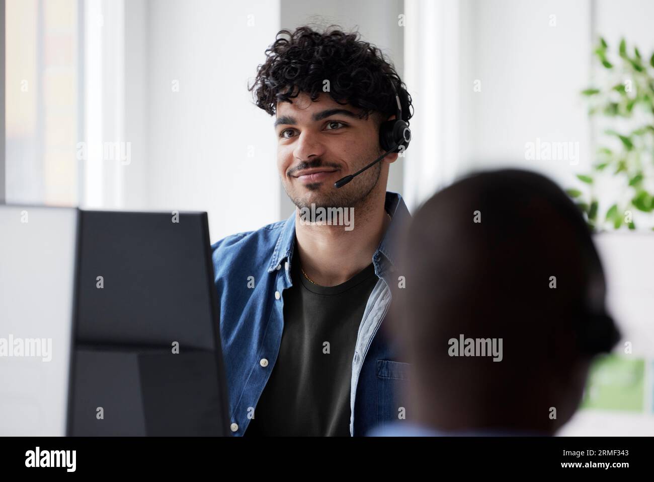 Young man using headset while sitting in office Stock Photo